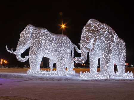 Glowing figures of mammoths at night in winter. Sculptures of mammoths, frame with luminous elements.の写真素材