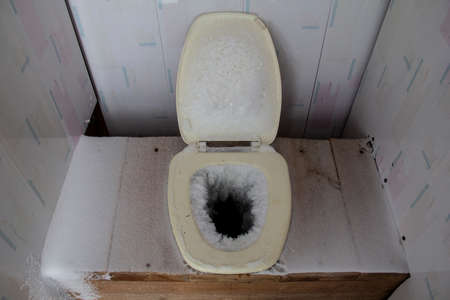 Frozen toilet. Frozen wooden outdoor toilet in severe frost. Country or country toiletの写真素材