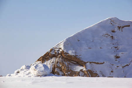 Sandy quarry covered with snow. Snow and sand - a northern landscape with mountains and a cliff.の写真素材