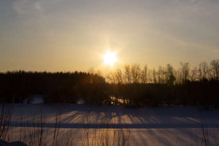 Winter fairy-tale nature of Siberia. The shadows of the trees fall on a snow-covered frozen lake.