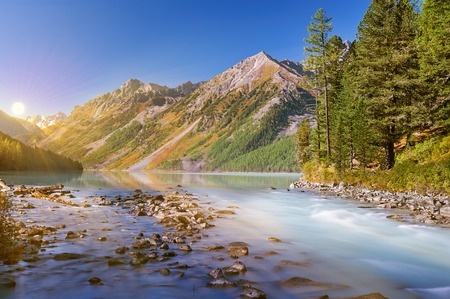 Sun among the mountain peaks. Beautiful summer landscape, mountain lake, Russia, Siberia, Altai mountains, Katun ridge.の写真素材