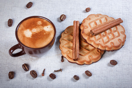 Espresso, cinnamon, cloves, cookies with chocolate on tablecloth, closeup.の写真素材