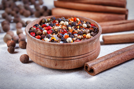 Spices in a wooden bowl, ceramic spoon, pepper, thyme, cinnamon, chili pepper, allspice.の写真素材