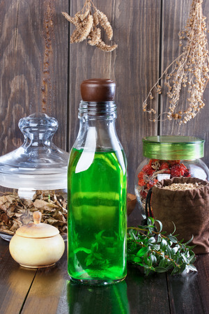 Therapeutic herbal tincture, alternative medicine, love potions, dried herbs on a wooden table.の写真素材