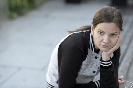 Ponderer girl sitting on a bench in the city