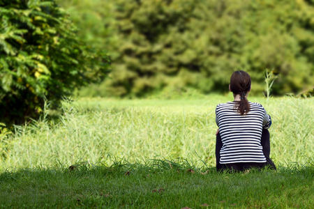 Girl sitting on the green grassの写真素材
