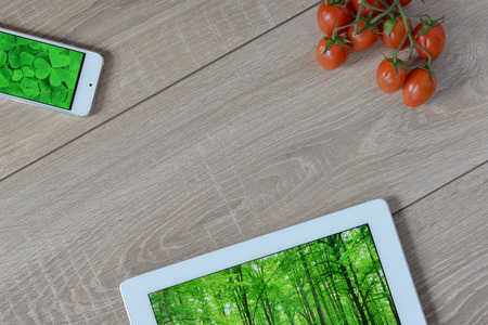 Natural and ecological life. Green forest in your phone and tablet. ?herry tomatoes on a wooden floor.の写真素材