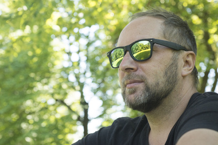 The man in the park in sunglasses. Beautiful reflection of the nature of the glasses.