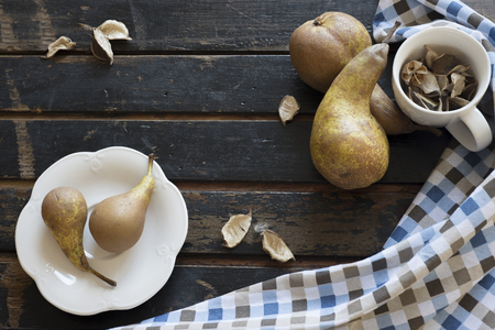 Pears and white porcelain cup with a saucer on a wooden table old.の写真素材