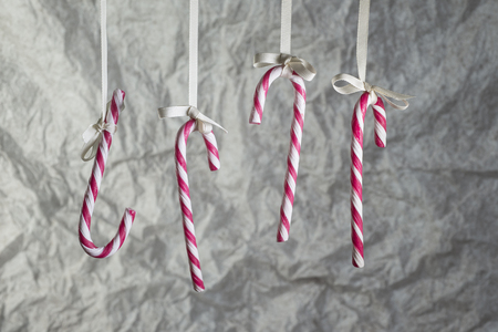 Candy Canes hanging on a ribbon on a background of crumpled wrapping paper.の写真素材