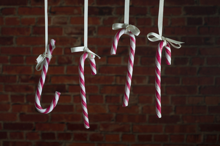 Candy Canes hanging on a ribbon on a background of a brick wall.の写真素材