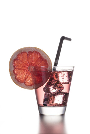 Fresh cocktail with grapefruit, ice and striped drinking straw on a white background.の写真素材