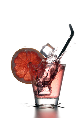 Fresh cocktail with grapefruit, ice and striped drinking straw on a white background.の写真素材