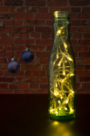 Christmas tree with a garland as a green bottle on the background wall of red brick.の写真素材