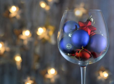 Transparent wine glass with ornaments for a festive Christmas tree. Against the background bokeh.の写真素材