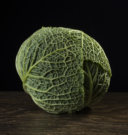 Ripe green savoy cabbage on a black background.の写真素材