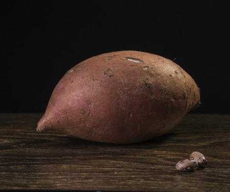 Sweet potatoes on a dark wooden table and black background.の写真素材