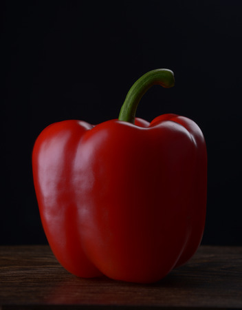 Red bell peppers on a dark wooden table on a black background.の写真素材