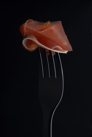Thinly sliced a small piece of dry meat on a fork.の写真素材