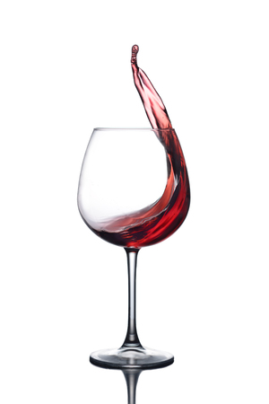 Splash of red wine in a glass on a white background with reflectionの写真素材