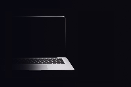 Portable modern silver computer on a black background. Half the computer in the shade.の写真素材