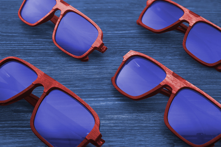 Sunglasses in red wooden natural frame and blue glasses on a beautiful blue background.の写真素材