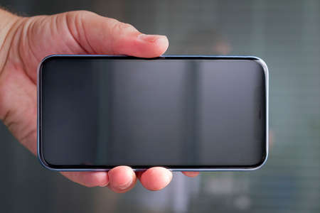 A man in a pink plaid shirt with a cell phone in his hand. White T-shirt.の写真素材