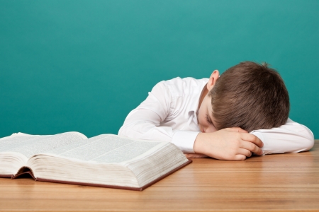 cheerful  little boy sitting at the table  and sleeps next to books  School conceptの写真素材