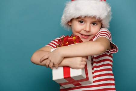 Smiling  funny child in Santa red hat holding Christmas gift in hand. Christmas concept.の写真素材