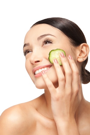 Close-up face of beautiful woman with clean fresh healthy skin and with cucumber slices around the cheeks. Isolated on whiteの写真素材