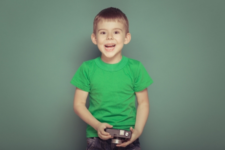 Cheerful smiling child (boy) holding a instant cameraの写真素材