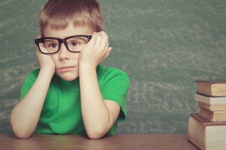 Cheerful  little boy sitting at the table. Looking at camera School conceptの写真素材