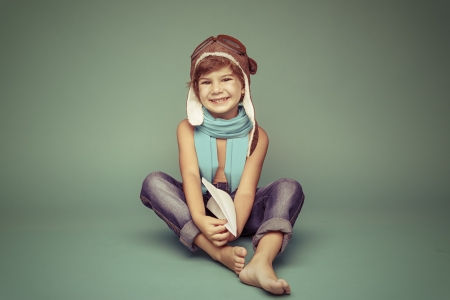 Cheerful smiling kid (boy)l in helmet on a green background. Vintage pilot (aviator) conceptの写真素材