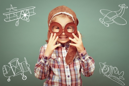 Beautiful smiling child (girl)  in helmet on a green background. Vintage pilot (aviator) conceptの写真素材