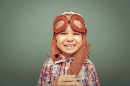 Beautiful smiling child (girl)  in helmet on a green background. Vintage pilot (aviator) conceptの写真素材