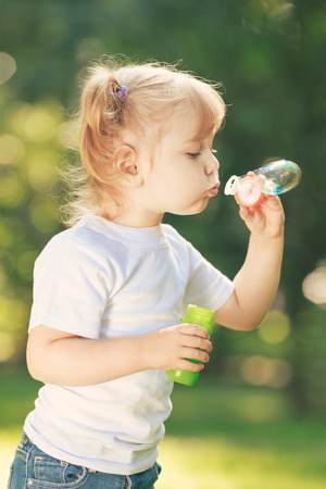 Little happy girl blowing soap bubbles in the parcの写真素材