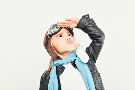 Beautiful smiling child (kid, girl) in helmet on a white background playing with a plane. Vintage...