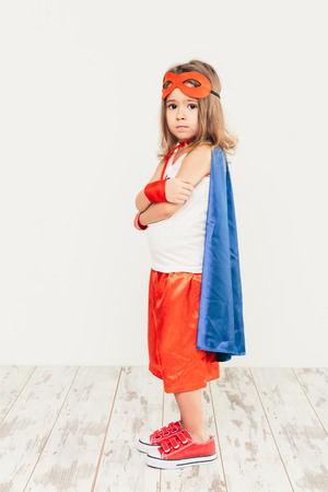 Funny little power super hero child (girl) in a blue raincoat. Superhero conceptの写真素材