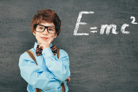Cheerful smiling little kid (boy) against  chalkboard. Looking at camera. School conceptの写真素材