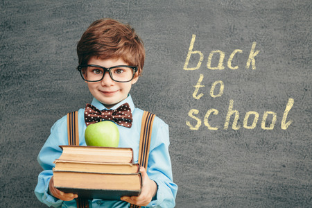Cheerful smiling little kid (boy) against chalkboard. Looking at camera. School conceptの写真素材
