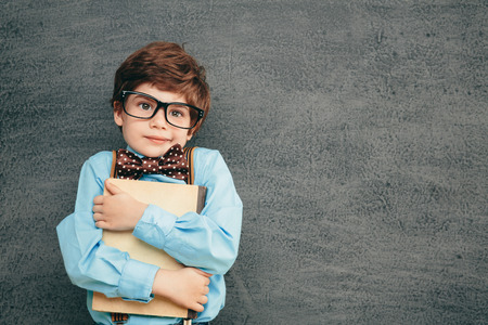 Cheerful smiling little kid (boy) against  chalkboard. Looking at camera. School conceptの写真素材