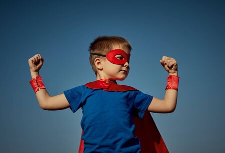 Funny little power super hero child (boy) in a red raincoat. Superhero concept