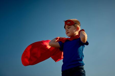 Funny little power super hero child (boy) in a red raincoat. Superhero concept.