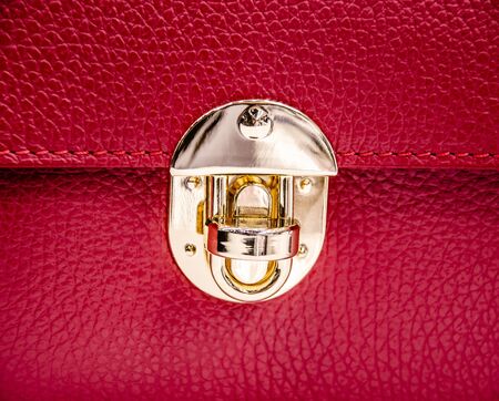 A fragment of a fashionable red leather ladies handbag with a shiny buckle.の写真素材
