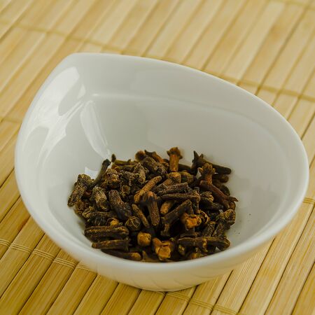 Seasoning dried cloves in a white bowl close-up.の写真素材