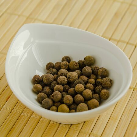 Seasoning allspice in a white bowl close-up.の写真素材