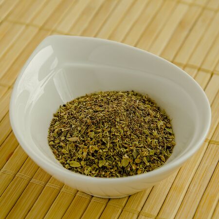 Seasoning oregano in a white bowl close-up.の写真素材