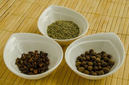 Seasoning allspice, cloves and rosemary in a white bowl close-up.の写真素材