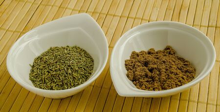 Seasoning ground coriander and rosemary in a white bowl close-up.の写真素材