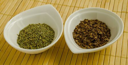 Seasoning dried dill and rosemary seeds in a white bowl close-up.の写真素材